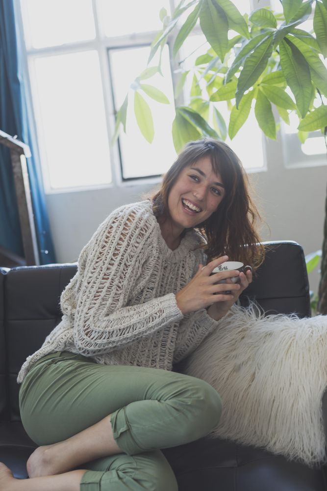 Female laughing on cozy sofa with cup of tea