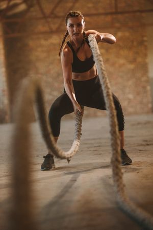 Fit woman athlete moving a rope in wave motion as part of fitness regime