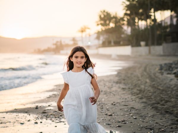 Excited girl running along beach in daylight