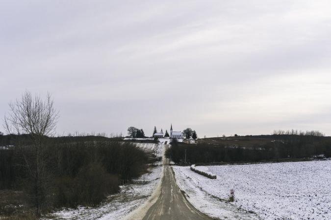 Rural road leading to to two churches against and overcast sky