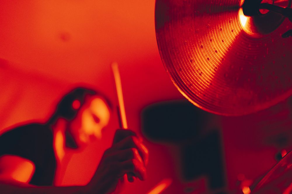Man with drumsticks playing on drums in redness