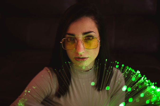 Young woman with fairy lights in darkness