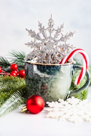 Mug of hot drink with candy cane and decorative pine and snowflake