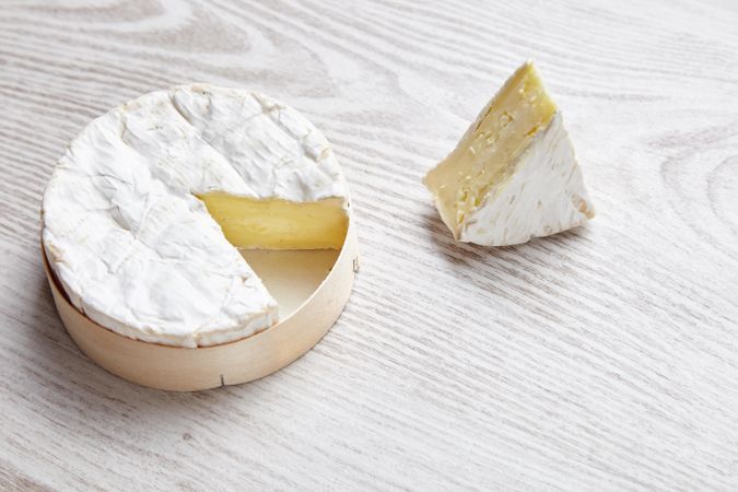 Brie cheese in wooden case with chunk cut out