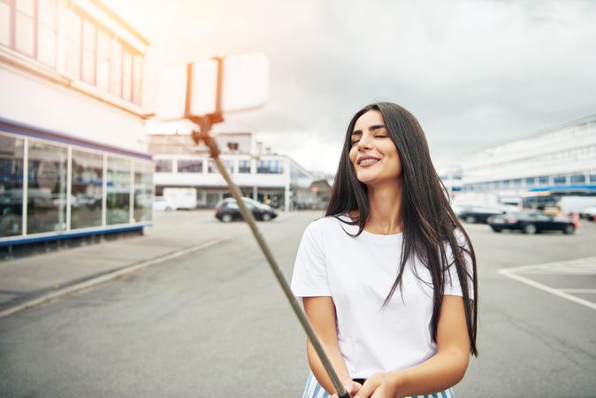 Brunette female posing for selfie on cloudy day in the street