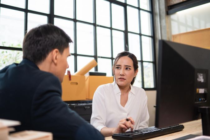 Male and female colleague discussing work at computer