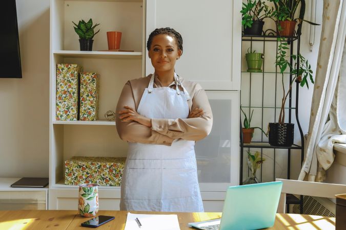 Portrait of confident female entrepreneur in work apron in bright office