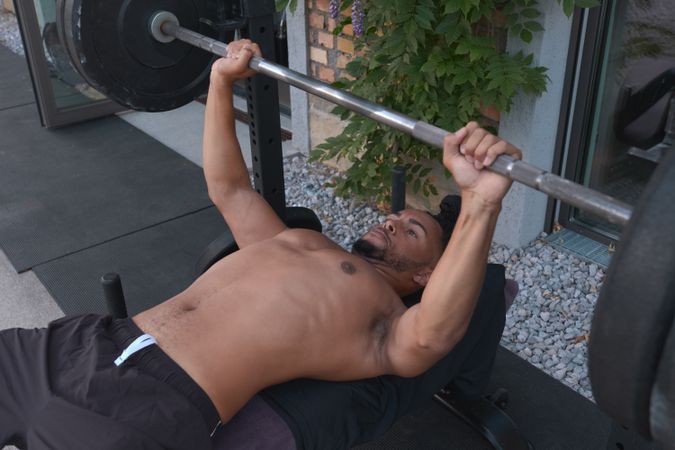 Black guy lifting barbell on street