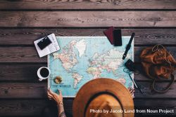 Young woman planning a vacation using world map and compass along with other travel accessories 0KmGM4