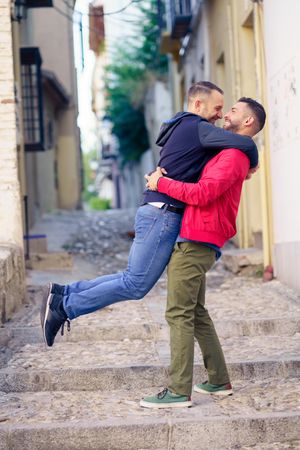 Man lifting up his partner in cute moment in narrow Spanish street