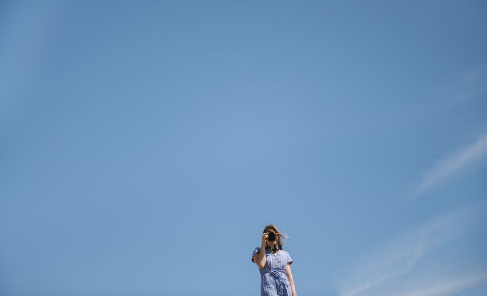 Traveling young female taking photo against blue sky