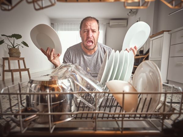 Man crying near dishwasher in kitchen