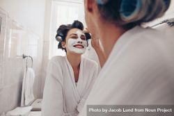 Smiling woman in bathrobe smiling while her mom applies face cream to her face at home 41yyj4