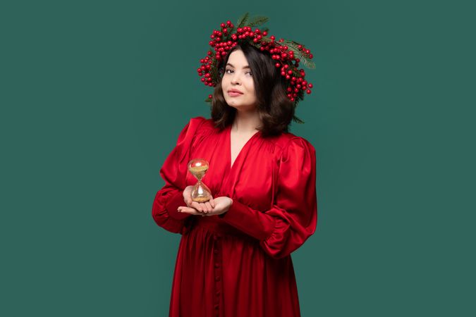 Stylish woman in red dress holding golden hourglass
