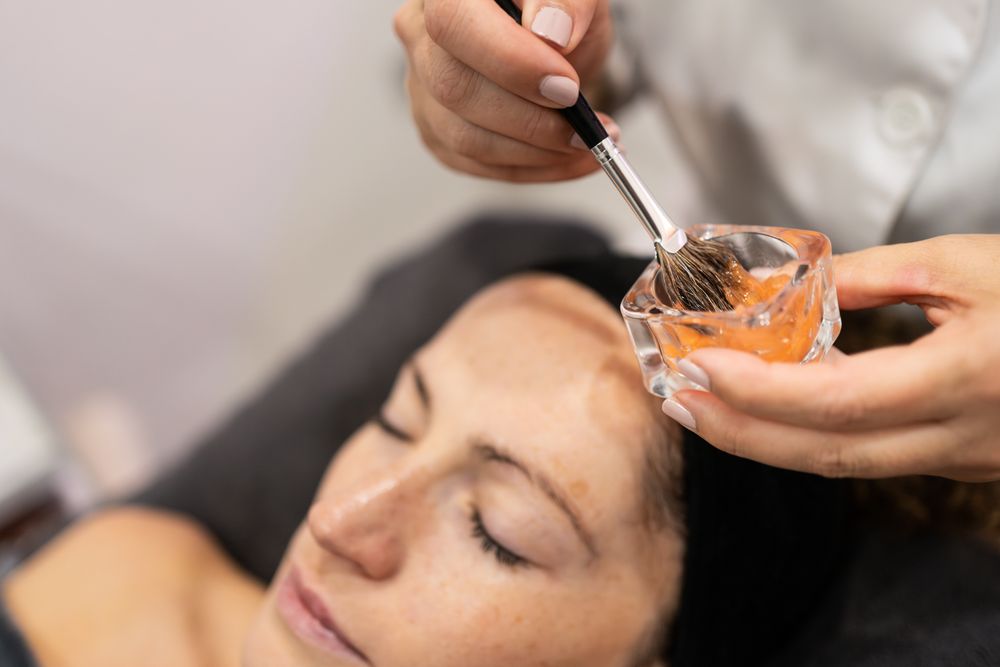 Unrecognizable beautician with client preparing product with brush