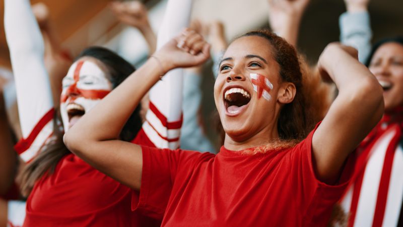 Female soccer fans of England watching and celebrating their team's victory