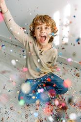 Cheerful boy having fun with confetti