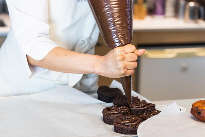 Anonymous woman adding chocolate cream on cakes