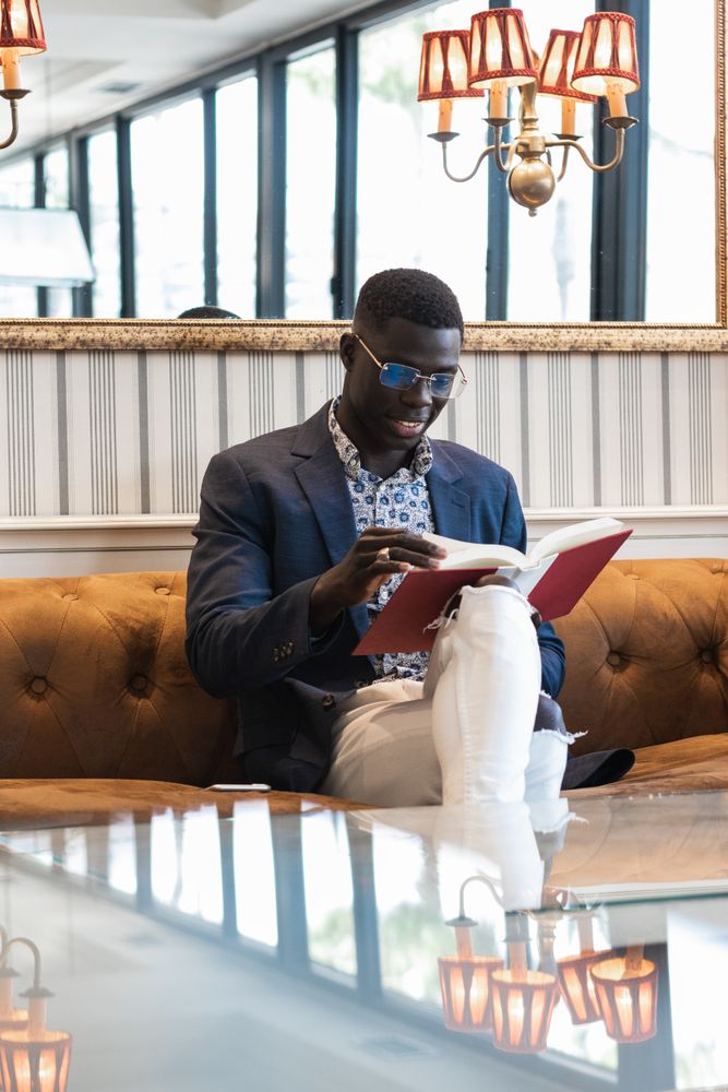 Pensive Black businessman reading book in cafe