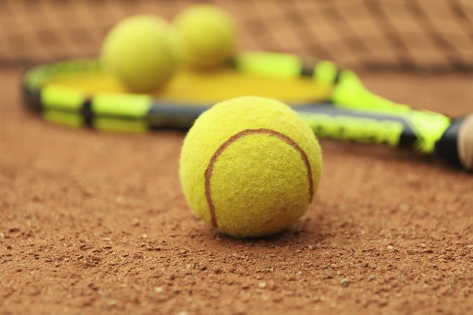 Tennis racquet with tennis balls on clay court