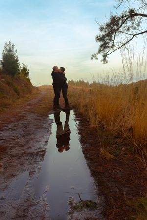 Men hugging and kissing near water puddle