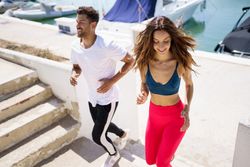 Man and woman exercising on stairs near waterfront