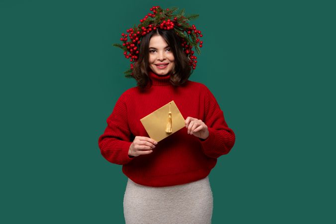 Cheerful woman in red sweater holding golden envelope