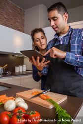 Couple checking digital tablet above cutting board 5apZa0