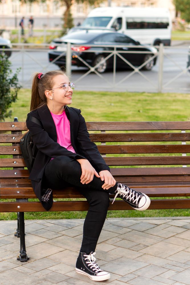 Girl sitting casually on bench and looking around.