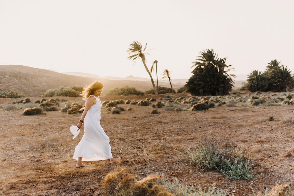 Woman in white dress in dry field in sunlight