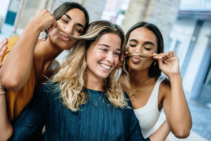 Group of female friends taking silly photo with hair