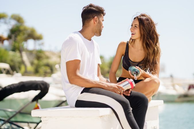 Man and woman sitting on pier on sunny day