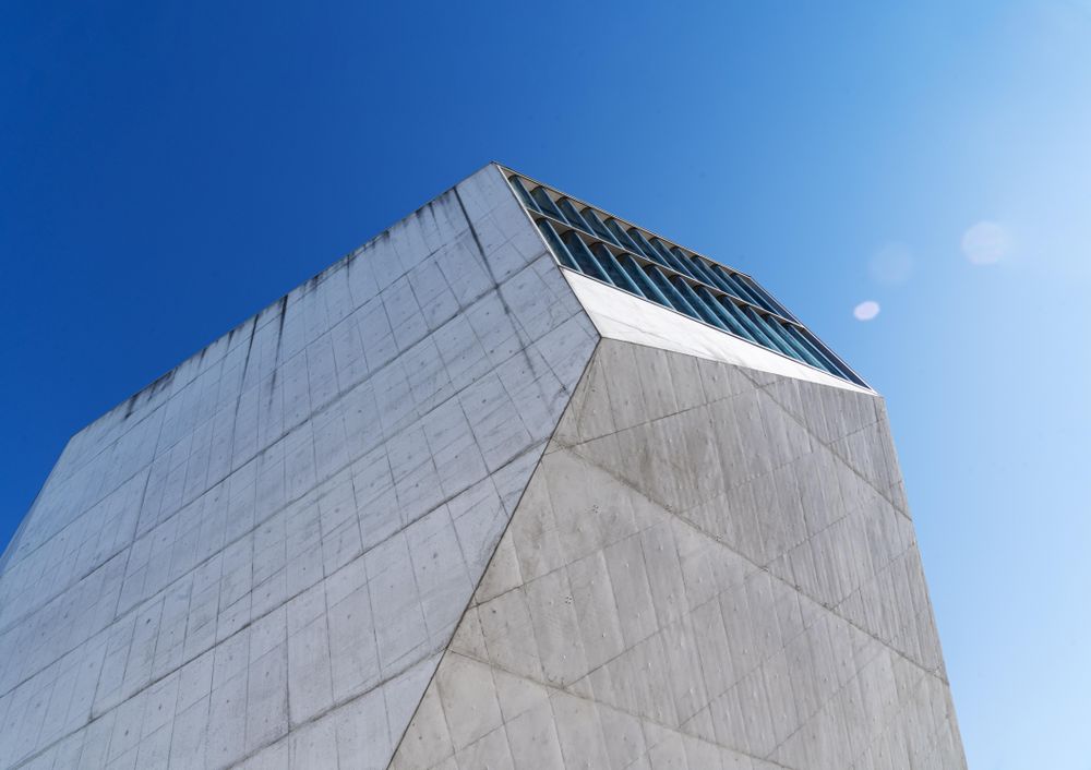 Looking up at vents on grey building against a blue sky