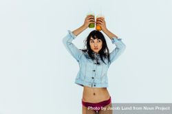 Woman in denim shirt and bikini bottoms holding two glasses of fresh juices on her head 5RKGD4