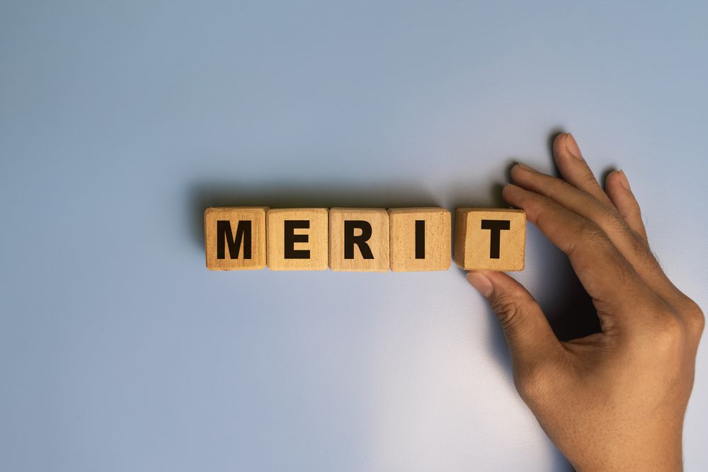 male hand put a wooden blocks with merit word isolated on blue background