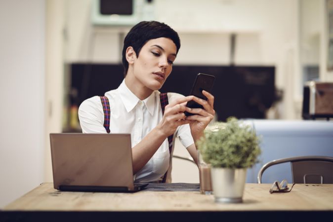 Woman in loft apartment on her smart phone while working at home