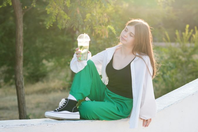 Teen girl drink soft drink on walk in park