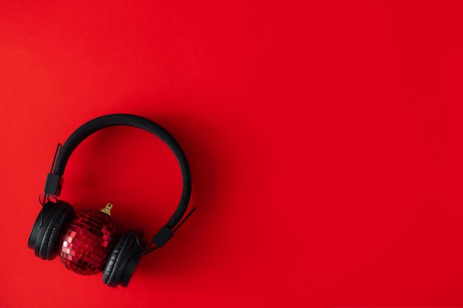Headphones around a red disco ball Christmas decoration on red background