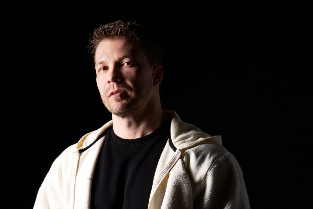 Serious man in white fleece jacket, dramatic lighting.