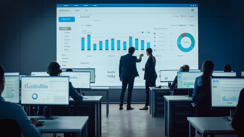 Business Executives Analyze Real-time Data on Giant Screen.
