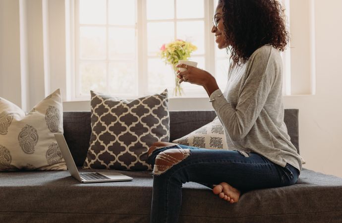 Businesswoman sitting on sofa at home and working on laptop