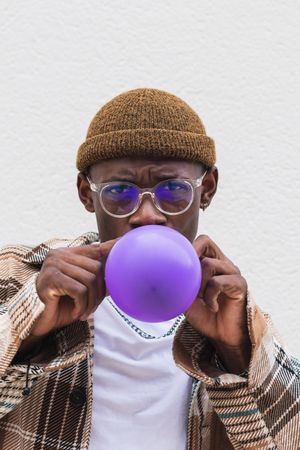 Trendy man blowing balloon