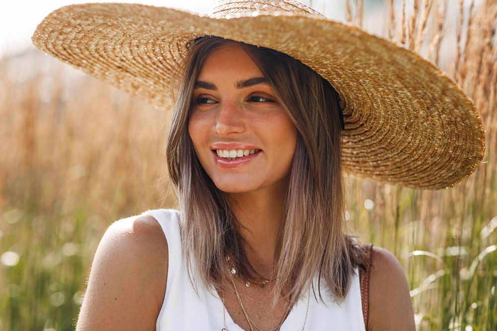 Smiling woman in field with straw hat