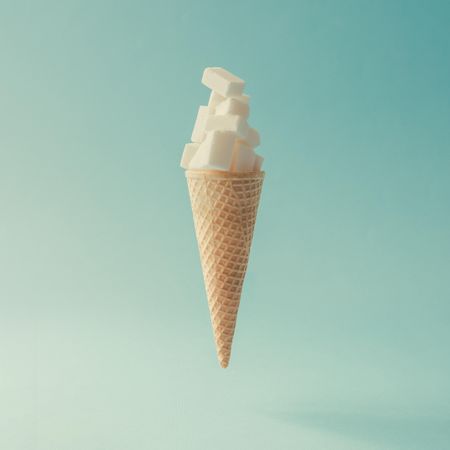 Ice cream cone with sugar cubes on light blue background