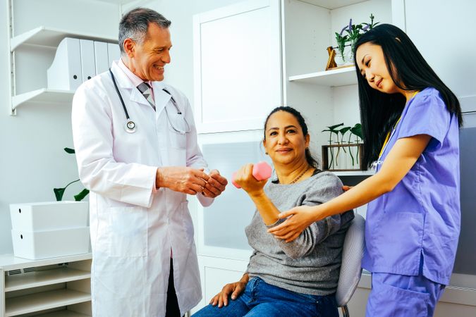 Doctor and physiotherapist working with patient during arm rehab exercises