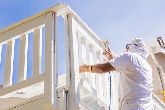 House Painter Spray Painting A Deck of A Home