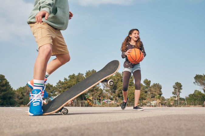 Teenage boy skater and girl with basketball ball exercising toge