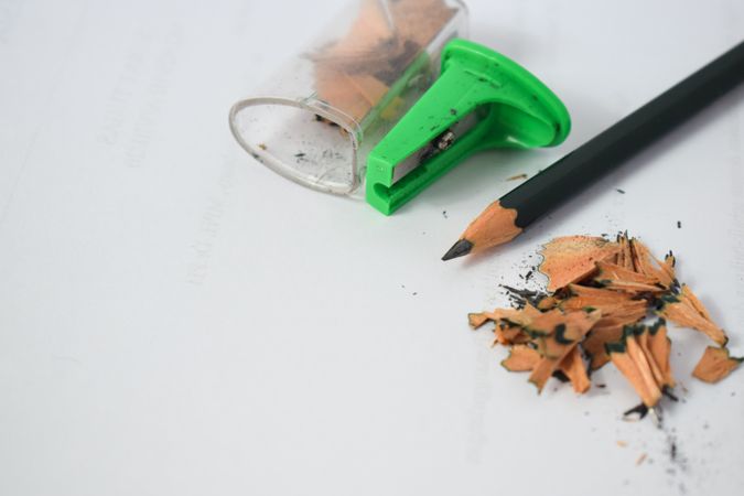 Pencil on table with shavings & green sharpener with copy space