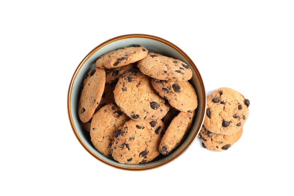 Bowl with tasty chocolate chip cookies on studio background, top view