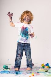 Cheerful boy covered with colorful paints